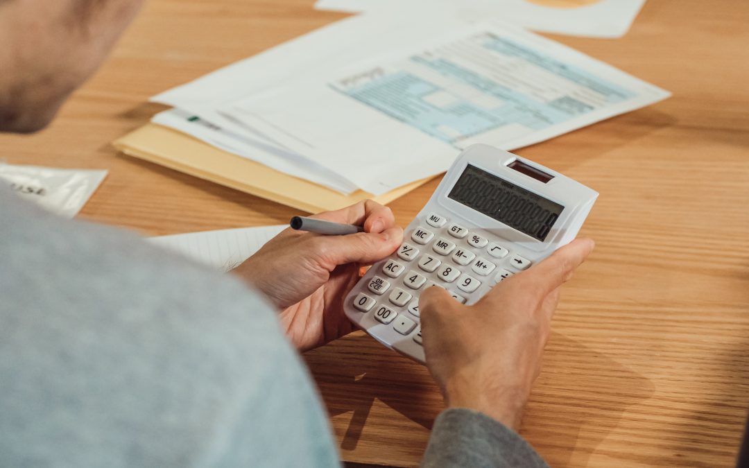 Person using a calculator at a desk with financial documents. Snap Finance Settlement Cancels $2.65M for Nebraskans